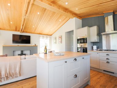 An open plan kitchen and living area with a kitchen island and a mounted television at 17 Meadow Retreat in Dobwalls