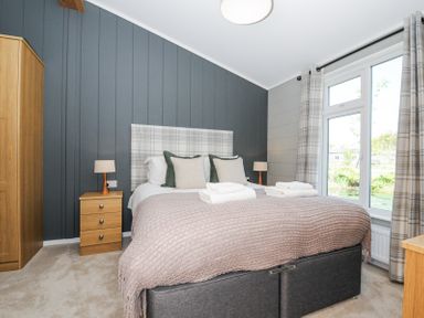 A bedroom with a double bed two bedside tables lamps a wardrobe and large window at 17 Meadow Retreat Dobwalls