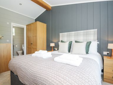A bedroom with a bed made with pillows and folded towels a wooden wardrobe and bedside tables with lamps at 17 Meadow Retreat in Dobwalls