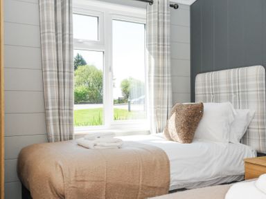 A bedroom with a single bed next to a window with plaid curtains at 17 Meadow Retreat in Dobwalls