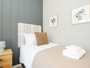 A bedroom with a single bed bedside table and two framed pictures on the wall at 17 Meadow Retreat in Dobwalls