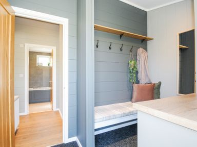 A hallway with a bench with pillows and hooks on the wall next to a bathroom at 17 Meadow Retreat in Dobwalls