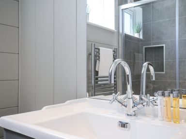 A bathroom sink with chrome faucets and toiletry bottles on the counter near a mirror and a towel rack at 17 Meadow Retreat in Dobwalls
