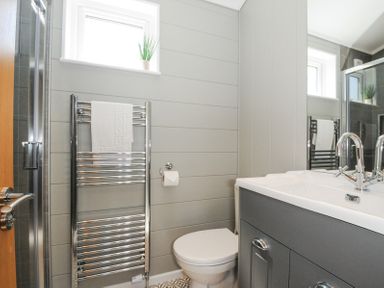 A bathroom with a toilet a sink with cabinet a towel rack and windows at 17 Meadow Retreat in Dobwalls