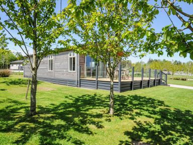 A wooden house with a deck surrounded by grass and trees at 17 Meadow Retreat in Dobwalls