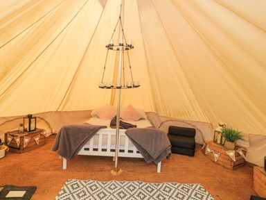 Interior of a bell tent with a bed a candle holder wooden crates and decorative items at Bell tent 3 Camerton near Timsbury