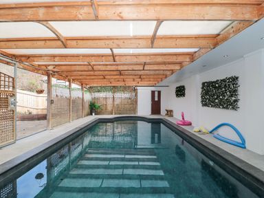 An indoor swimming pool with wooden beams overhead and lattice walls at Bell tent 4 Camerton near Timsbury