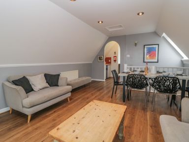 A living room with a sofa cushions wooden coffee table dining table and chairs at Valley Lodge 38 in St Ann's Chapel Cornwall