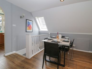 A dining area with a table set with bowls plates and utensils next to a staircase and a window at Valley Lodge 38 in St Ann's Chapel Cornwall