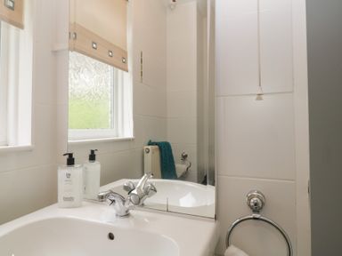 A bathroom sink with a faucet soap dispenser and mirror at Valley Lodge 38 in St Ann's Chapel Cornwall