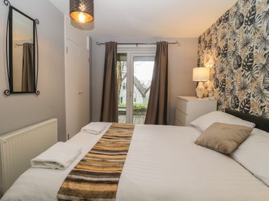A bedroom with a bed a chest of drawers a lamp and curtains at Valley Lodge 38 St Ann's Chapel Cornwall