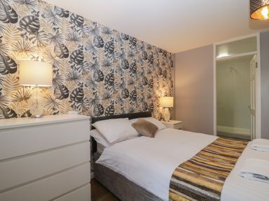 A bedroom with a bed framed by two bedside tables with lamps and a chest of drawers at Valley Lodge 38 in St Ann's Chapel Cornwall