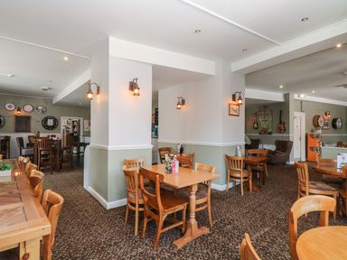 An interior dining area with wooden tables and chairs wall lights and decor at Valley Lodge 38 in St Ann's Chapel Cornwall