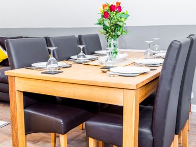 A dining table set with plates glasses utensils and a flower vase in a room at Valley Lodge 40 St Ann's Chapel Cornwall