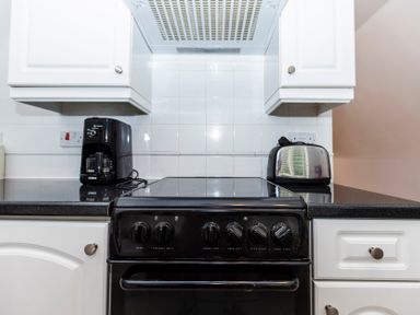 A kitchen countertop with a black stove in the center a coffee maker to the left and a toaster to the right at Valley Lodge 3 in St Ann's Chapel Cornwall