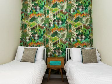 A bedroom with two single beds separated by a wooden nightstand and a wall with patterned green wallpaper at Valley Lodge 3 St Ann's Chapel Cornwall