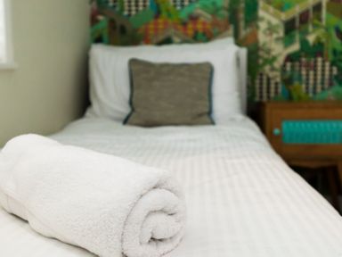 A bed with a rolled white towel on it and a pillow at Valley Lodge 3 St Ann's Chapel Cornwall