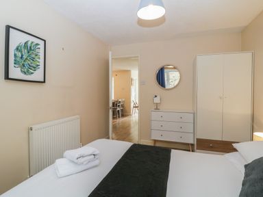 A bedroom with a double bed and folded towels near a chest of drawers and wardrobe at 26 Manorcombe St Ann's Chapel Cornwall