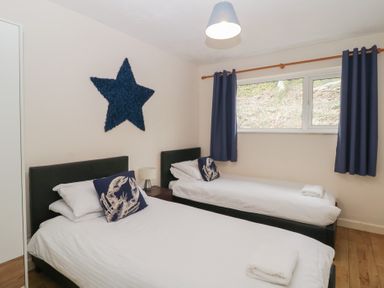 A bedroom with two single beds blue curtains and a blue star wall decoration at 26 Manorcombe in St Ann's Chapel Cornwall