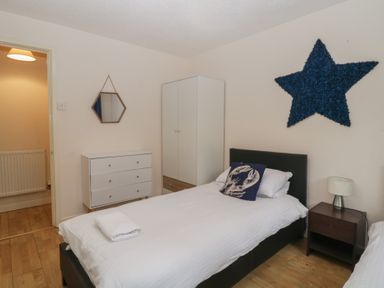 A bedroom with a single bed a nightstand with a lamp a wardrobe a chest of drawers and a wall mirror at 26 Manorcombe in St Anns Chapel Cornwall
