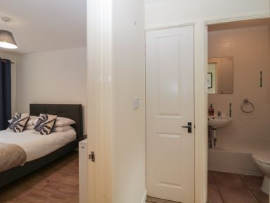 A bedroom with a bed and pillows next to a bathroom with a sink and toilet at 26 Manorcombe in St Ann's Chapel Cornwall