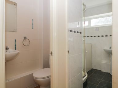 A bathroom with a toilet and sink next to a shower enclosure and sink at 26 Manorcombe in St Anns Chapel Cornwall