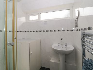 A bathroom with a sink pedestal mirror towel rack and a shower cubicle at 26 Manorcombe in St Ann's Chapel Cornwall