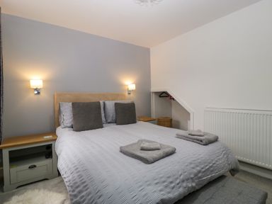 A bedroom with a double bed two bedside tables and wall lights at Colliers Cottage in Cinderford