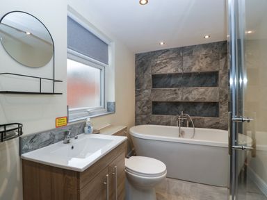 A bathroom with a sink cabinet toilet bathtub and a window at Colliers Cottage in Cinderford