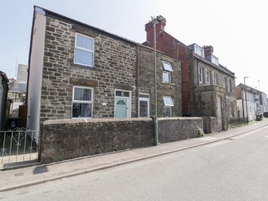 A street view of stone houses with a low stone wall and a lamppost in front at Colliers Cottage in Cinderford