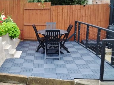 A garden with a table and chairs on a wooden deck at Colliers Cottage in Cinderford