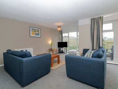 A living room with two blue sofas a wooden coffee table a small TV and striped curtains at Tamar Cottages 34 St Ann's Chapel Cornwall