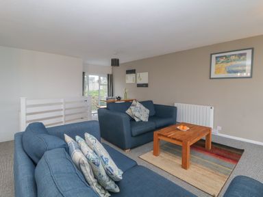 A living room with two blue sofas a wooden coffee table with oranges and framed pictures on the wall at Tamar Cottages 34 in St Ann's Chapel Cornwall