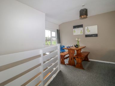 A dining area with a wooden table and benches next to a window with a blue chair at Tamar Cottages 34 in St Ann's Chapel Cornwall