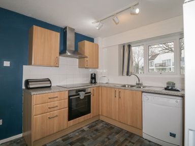 A kitchen with wooden cabinets a stove oven dishwasher sink and window at Tamar Cottages 34 St Ann's Chapel Cornwall