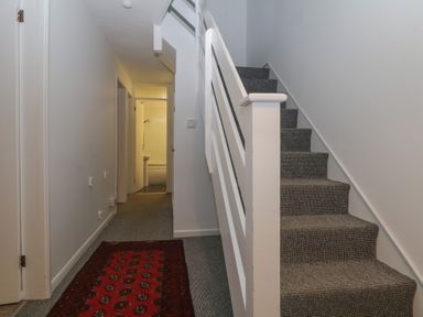 A hallway with carpeted stairs and a red runner rug leading to a bathroom at Tamar Cottages 34 in St Ann's Chapel Cornwall