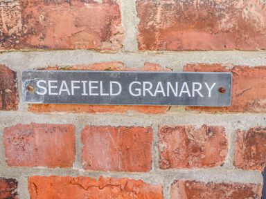 A metal sign with the text Seafield Granary mounted on a brick wall at Seafield Granary in Alnmouth