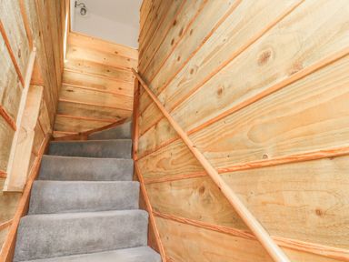 A carpeted staircase with wooden paneled walls and a wooden handrail at Seafield Granary in Alnmouth