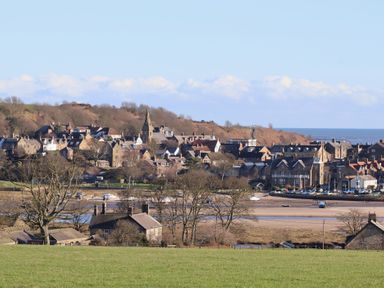 A view of a village with houses and a church near the sea at Seafield Granary in Alnmouth