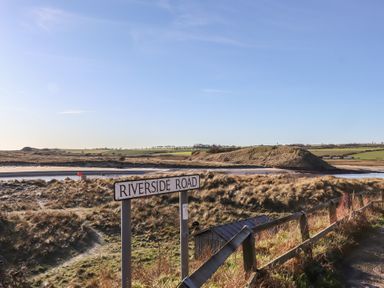 A landscape view featuring Riverside Road sign near grass and water at Seafield Granary, Alnmouth