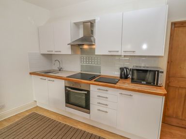 A kitchen with white cabinets wooden countertop and appliances at Seafield Coach House in Alnmouth