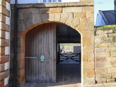 A stone archway entrance with a wooden door at Seafield Coach House Alnmouth