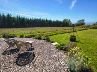 A garden with chairs and a fire pit at Fir Tree Shepherd's Hut in Llanon