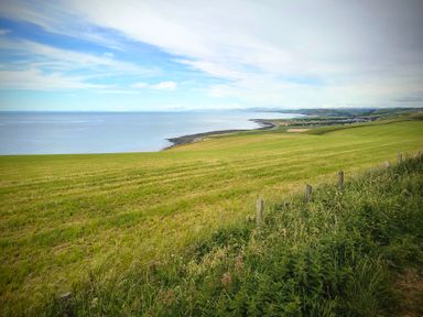 A view of the sea and grassland at Fir Tree Shepherd's Hut in Llanon