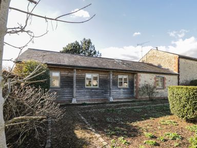 Exterior view of a single story stone and wooden building with windows and a garden in front at South Barn Cottage in Hatford near Stanford In The Vale