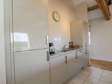 A kitchen with white cabinets a sink coffee maker and a clock on the wall at South Barn Cottage Hatford near Stanford In The Vale