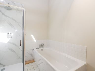 A bathroom with a bathtub and a glass-enclosed shower at South Barn Cottage in Hatford near Stanford In The Vale