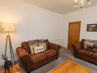 A living room with two brown sofas pillows a lamp a wooden door and a wooden table at The Bungalow in Whitby