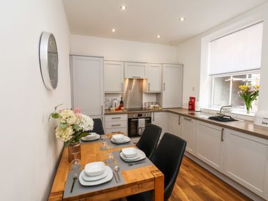 A kitchen with a wooden dining table set for four and cabinetry along the walls at The Bungalow in Whitby
