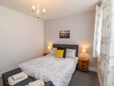 A bedroom with a double bed bedside tables lamps and a small seat with towels at The Bungalow in Whitby